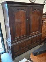 An 18th century and later oak cupboard with panelled doors on two drawer base (2 sections, missing