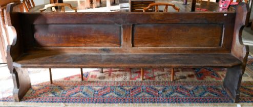 An antique stained pine pew, 220 cm wide