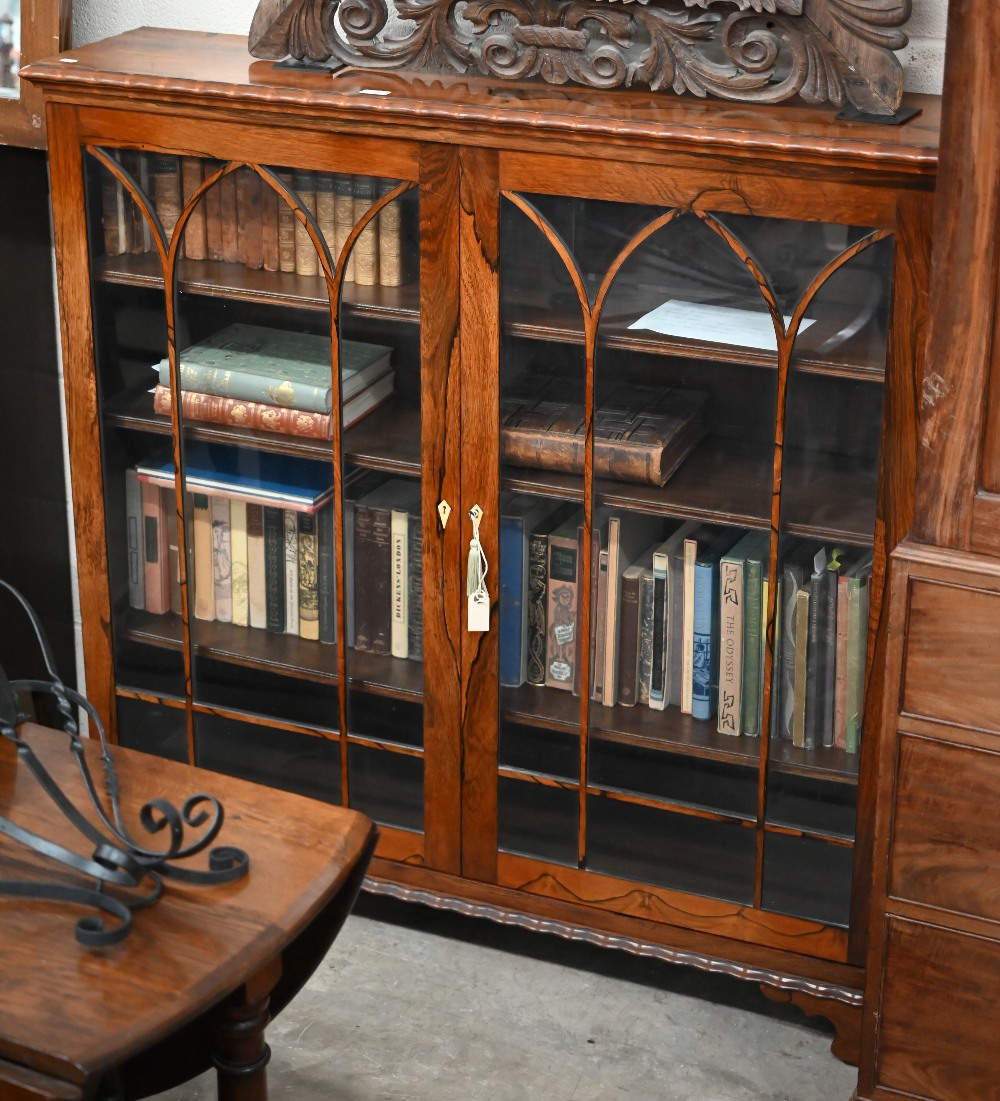 A Victorian rosewood 'piano bookcase' the pair of glazed doors enclosing three shelves standing on