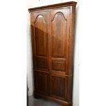 A Georgian style oak floor standing corner cabinet (one piece) with panelled cupboard doors,