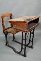 A Victorian cast iron and oak student/school desk, the slope top carved with multiple graffiti,