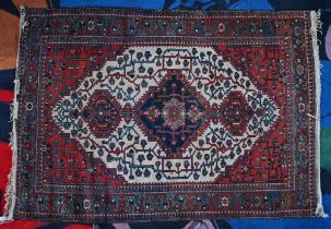 An early 20th century Persian Bakhari rug, the navy triple medallion on cream gorund with red