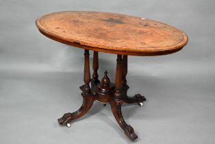 A Victorian inlaid figured walnut centre table, the oval top raised on four to swept legs, on