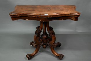 A Victorian walnut card table, the fold over serpentine top with baize lining, raise on moulded