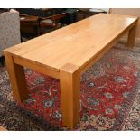 A large contemporary light oak corner-leg dining table, rectangular top with square supports (