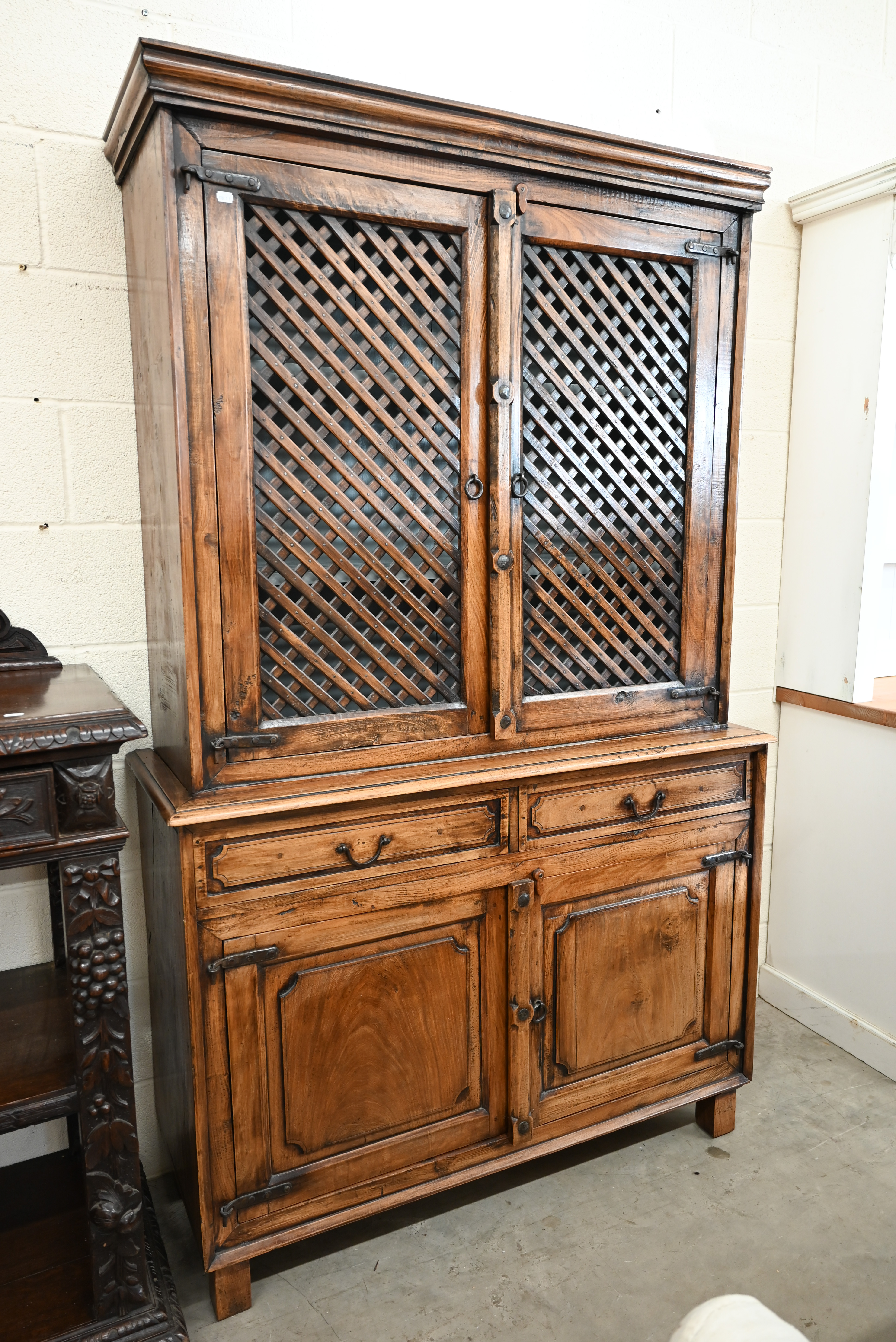 An Indian hardwood two part cabinet with open lattice panelled doors on base with two drawers and