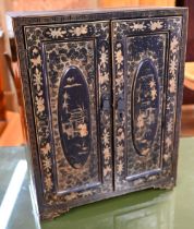 An early 20th century Japanese black lacquered table cabinet with two doors enclosing five