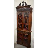 A carved mahogany floor-standing corner cabinet in two parts, with astragal glazed doors and