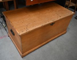 An antique pine blanket chest with hinged top and iron side handles, 98 cm wide x 52 cm deep x 46 cm