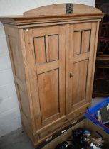 An antique pine knock-down wardrobe with twin panelled doors enclosing open hanging space on
