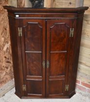 A Georgian mahogany corner hanging cupboard, the dentil moulded cornice over panelled doors
