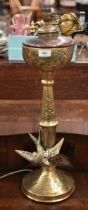 An antique copper and brass newel-post oil-lamp, mounted with a swallow, 66 cm high overall (