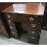 A George III mahogany kneehole desk with seven drawers and secret frieze drawer over recessed