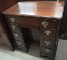 A George III mahogany kneehole desk with seven drawers and secret frieze drawer over recessed