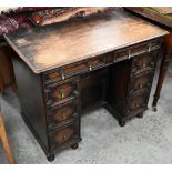 An early 20th century oak Jacobean style kneehole desk, eight drawers around central niche with