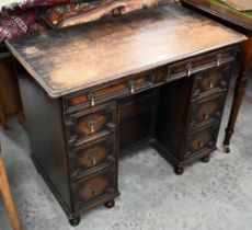 An early 20th century oak Jacobean style kneehole desk, eight drawers around central niche with