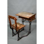 A Victorian cast iron and oak student/school desk, the slope top carved with multiple graffiti,