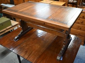 An Ercol elm draw leaf dining table, on shaped trestle ends united by a mid-height centre stretcher,