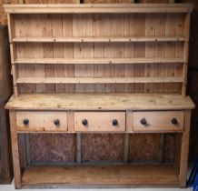 A Victorian stripped pine kitchen dresser, the three tier tongue & grove backed rack over three