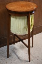 A satinwood work table, the circular hinged top enclosing a pleated fabric storage well, raised on