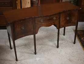 An antique mahogany serpentine front sideboard, centred by a drawer flanked by a cupboard and deep