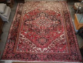 A Persian Heriz carpet, large central medalion on red ground, dark brown rosette border, 387 cm x