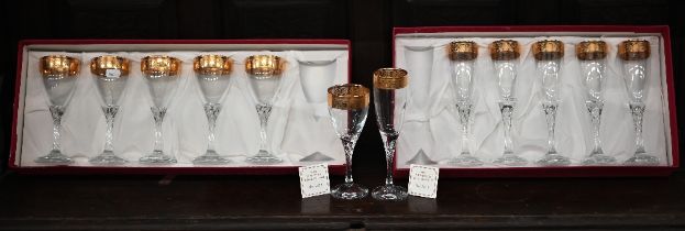 A boxed set of six gilt-rimmed champagne flutes and six wine glasses to match