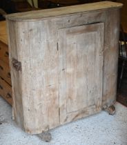 An antique French stripped pine cupboard, with rounded ends centred by a single door, raised on