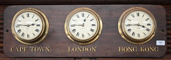 A set of three ship's bulkhead clocks mounted on a plaque inscribed 'Cape Town' 'London' and 'Hong