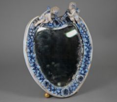 An antique Sitzendorf porcelain heart-shaped mirror surmouted by two cherubs, on floral-encrusted