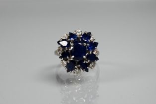 A Mappin & Webb sapphire and diamond cluster ring formed of central blue sapphire flower with