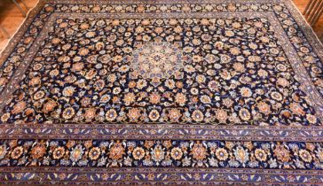 Central Persian signed Kashan carpet, predominantly blue centred by a floral medallion, 380 cm x 270