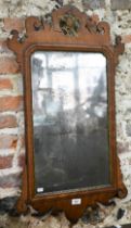 An antique fret-cut wall mirror, surmounted by a ho-ho bird, the silvered plate tarnished with