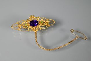 A Victorian 15ct gold brooch of open scroll form, set central oval purple stone with two peridot