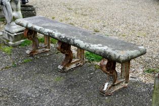 A weathered antique stone and cast iron garden bench, the rectangular seat raised on three