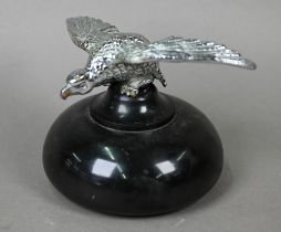 A vintage chrome spreadeagle car mascot, 4 cm high x 18 cm wingspan, mounted on a turned stone