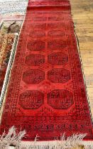 An Afghan red ground runner with two rows of guls, 320 cm x 91 cm