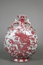 A 20th century Chinese copper-red and white moon flask vase with applied chilong dragon handles,