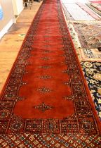 A Bokhara long red ground runner of repeating designs, 629 x 79 cm