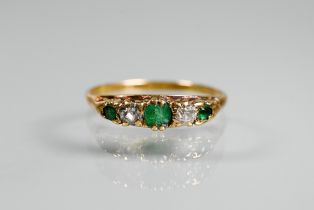 An antique emerald and diamond ring, the three graduated emeralds with two old cut diamonds