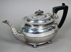 An Edwardian silver oval teapot with gadrooned rim and half reeding, composite handle and finial, on