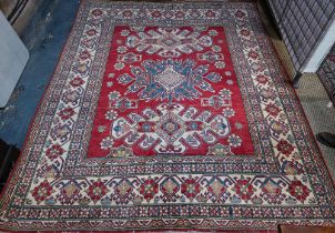 A contemporary Kazak carpet with pale red ground and stylized floral design within camel ground