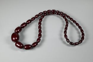 A graduated dark red amber bead necklace, approx 3 x 2 cm and 1 x 0.5 cm, 52.6g