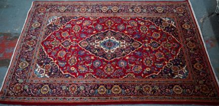 An old central Persian Kashan rug, the wine-red ground centred by a blue ground floral medallion,