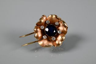 A yellow metal fur clip in the form of a six petal flower head with blue sapphire centre with six