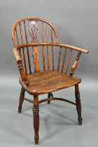 An old Windsor elbow chair with elm seat and raised over a crinoline stretcher