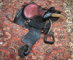 A vintage tooled leather American Western style saddle, with straps/stirrups but a/f