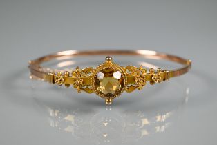 A Victorian 9ct yellow gold half hinged bangle with flower and scroll decoration and central