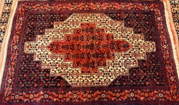 A Persian Senneh rug, the traditional blue ground centred by a floral and animal design panel, 173