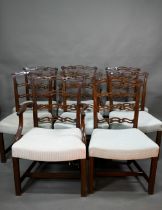 A set of eight Georgian style walnut dining chairs with pierced wavy splats over overstuffed seats